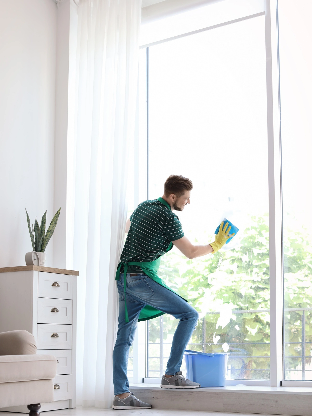 Nettoyage professionnel : Un homme lave les vitres d'une grande baie vitrée, garantissant des fenêtres impeccablement propres et une vue dégagée dans un environnement lumineux.